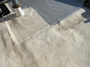 Roof-Coating-Kentwood-MI-Michigan-2 | JM Roofing Solutions Close-up of a white powdery material spread on a blue tarp, with a small trowel resting at the edge.