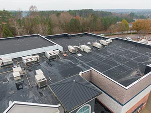 Flat-Roof-Repair-Wyoming-MI-Michigan-1 | JM Roofing Solutions Flat rooftop with multiple HVAC units and vents; trees in the distance.